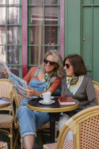 Carré de soie dans le quotidien – Maison Devienne Deux femmes lisant avec des carrés de soie en terrasse