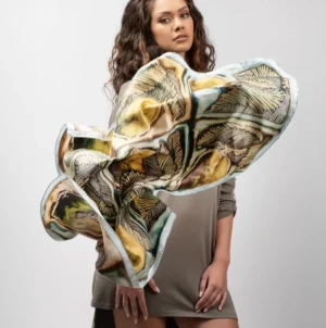 Maison Devienne silk scarf “Zeste de Paradis” showcased on a model. The natural fluidity of silk highlights the tropical colors and refined artistic motifs.