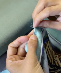 Hands finishing a luxury silk scarf with a traditional hand-rolled hem
