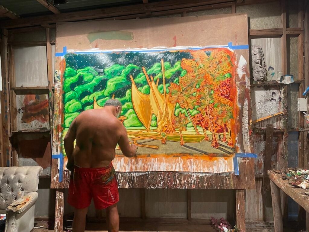 Louis Devienne peint dans son atelier un paysage polynésien