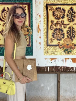 Femme posant avec une toile de Louis Devienne dans son atelier.