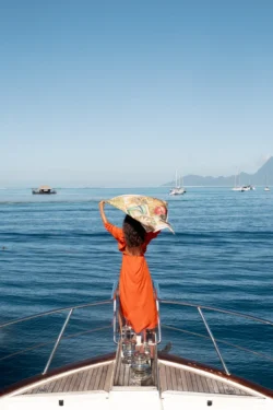 Femme sur un bateau à Tahiti avec un carré de soie Maison Devienne au vent